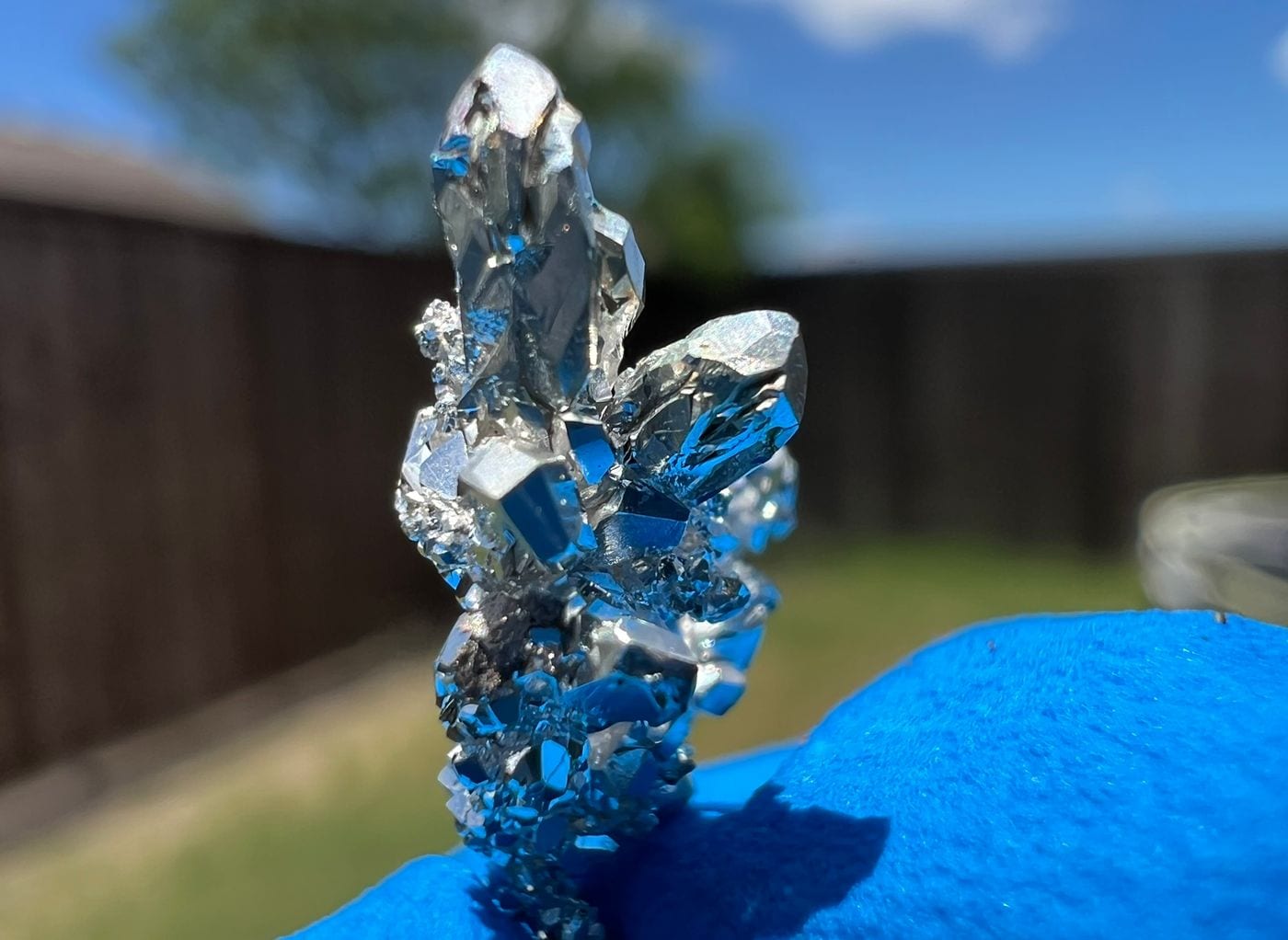 Silvery stair-stepped bismuth hopper crystal on a blue surface
